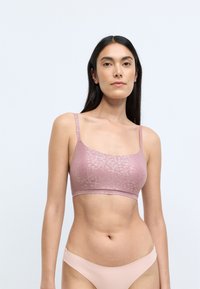 Lyserød bralette med en struktureret leopardprint, der har tynde stropper og et sømløst design. Glat stof med en blød overflade.