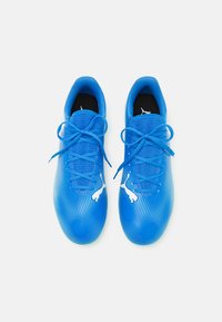 Zapatillas deportivas azules con un upper texturizado, que presenta un patrón de puntos en degradado, un acento de logo blanco y cordones azul a juego.