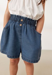 Denim shorts med elastisk talje, to sidelommer og træknapper. Tøjet har en blød tekstur og en mørkeblå farve.