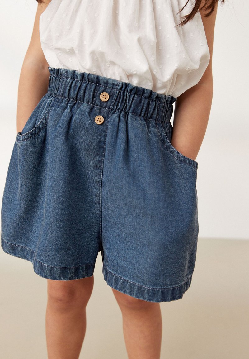 Shorts di jeans con una vita elastica, due tasche laterali e bottoni in legno. Il tessuto presenta una consistenza morbida e un colore blu scuro.