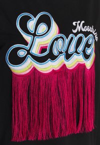 Svart plagg med ordet "Love" broderat i flerfärgat tråd, med en rosa fransdetalj längst ner.