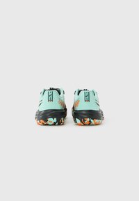 Pair of mint green athletic shoes with black soles and colorful orange, blue, and white patterned tread, viewed from the back on a white background.