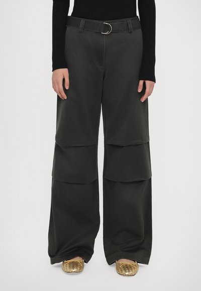 Pantaloni largi de culoare verde închis cu detalii din țesături stratificate, o curea asortată cu o cataramă din aliaj argintiu și o textură netedă.
