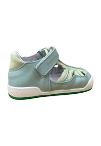 Zapato de cuero azul claro con suela blanca y acentos verdes. Presenta una correa de Velcro y un diseño perforado en los laterales para ventilación.