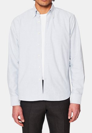 Randig skjorta i ljusblått och vitt bomull, med krage, långa ärmar och rak passform; bärs över en vit t-shirt.