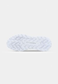 White sneaker sole featuring a textured rubber surface with zigzag pattern, embossed logo, and distinct tread design for grip.