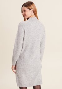 Hellgraues gestricktes Kleid mit hohem Kragen, gerippten Bündchen und seitlichen Schlitzen; weiche Textur und mittellanges Design.