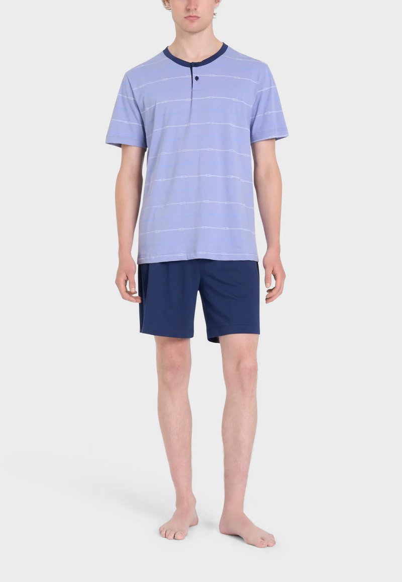 Camicia corta a maniche con righe bianche orizzontali di colore lilla chiaro e colletto blu navy; abbinata a pantaloni corti blu navy. Vestibilità casual e comoda.