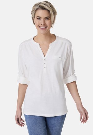 Weiße, leichte Bluse mit V-Ausschnitt, Knopfleiste und aufgerollten Ärmeln. Mit einer kleinen Brusttasche und einem weichen, strukturierten Stoff.