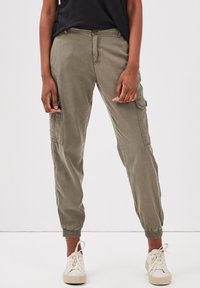 Pantalon cargo vert olive avec des poignets élastiques, poches latérales et fermeture à bouton à l'avant. Fabriqué à partir d'un tissu doux et léger. Coupe décontractée.