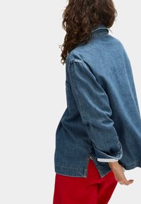 Denimjack met een relaxte pasvorm, lichtblauwe kleur, lange mouwen en zijslits. Bevat een enkele borstzak en opgerolde manchetten.