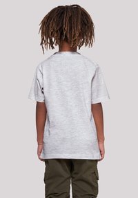 Light gray, short-sleeved t-shirt made of cotton blend, with a round neckline, viewed from the back, paired with olive green cargo pants.
