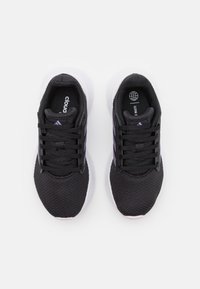 Schwarze Sportschuhe mit einem Obermaterial aus Mesh, weißer Sohle und lila Akzenten. Merkmale sind runde Schnürsenkel und ein gepolsterter Schaft.