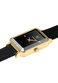 Montre rectangulaire dorée avec un cadran noir, une lunette brillante et un bracelet en cuir noir. Présente une couronne et des aiguilles simples pour les heures et les minutes.