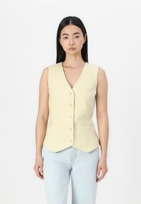 Gilet sans manches de couleur jaune clair avec décolleté en V, six boutons à l'avant et poches sur les côtés. Coupe ajustée avec un ourlet pointu et une texture de tissu lisse.