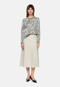 Light gray skater skirt paired with a black and white graphic print long-sleeve top featuring a round neckline and contrasting edges.