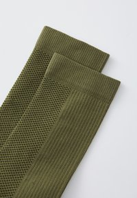 Gröna stickade strumpor med en texturerad mönstring och ribbade detaljer. Materialet är mjukt och designen är funktionell och sitter nära kroppen.