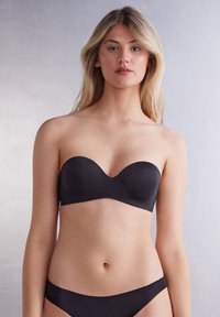 Sort strapless bh lavet af glat stof, med en buet halsudskæring og sømløst design, parret med matchende bikiniunderdel.