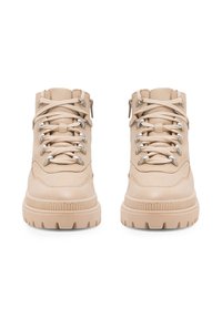 Beez värvi nahast pahklabajala saapad, millel on tekstuuriga viimistlus, metallist silmadega, lame pael ja lõhkeseade, samuti külgne tõmblukk, mis lihtsustab jalga panemist.