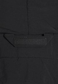 Svart ytterplaggstextil med en slät yta har en rektangulär, präglad DIDRIKSONS-logotyp i centrum, vilket betonar rena designlinjer.