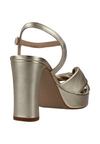 Sandalo con tacco alto in metallo dorato, con tacco largo, cinturino alla caviglia e fasce incrociate sulla punta. Texture liscia e soletta imbottita.