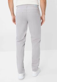 Pantaloni grigi chiari realizzati in un tessuto morbido, con un design slim fit, cinque tasche e dettagli di cucitura discreti.