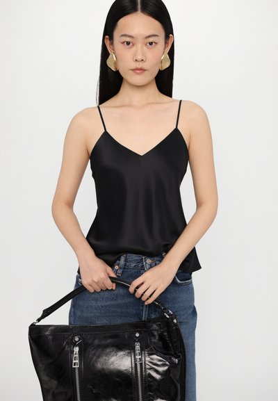 Camisole negru din satin cu bretele subțiri, design cu decolteu în V, asociat cu blugi din denim albastru cu talie înaltă și o geantă totem neagră lucioasă cu fermoare.