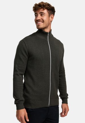 Mørkegrønn zip-up genser med et teksturert herringbone-mønster, ribbestrikkede mansjetter og en stående krage med en kontrastfarget hvit glidelås.