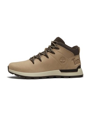 Scarponcino da trekking color cognac con colletto imbottito marrone scuro, chiusura frontale con lacci, logo ad albero in rilievo sul lato e suola spessa bianca e nera.