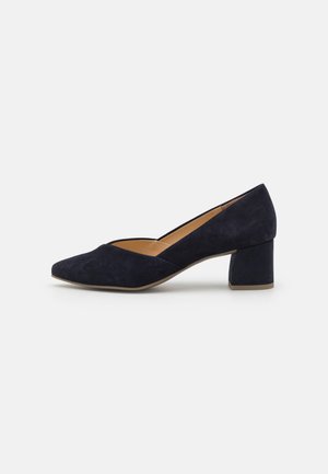 Navy blue suede block-heel pumps featuring a pointed toe and v-cut design, with a smooth interior and textured exterior.