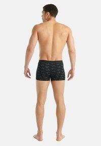 Czarne bokserki z geometrycznym wzorem, wykonane z miękkiego materiału, z elastycznym pasem, o dopasowanym kroju i długości do połowy uda.