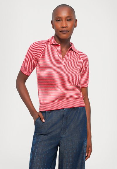 Polo a righe rosse e bianche con maniche corte, caratterizzato da un colletto e una texture a costine. Abbinato a pantaloni in denim blu scuro con dettagli.