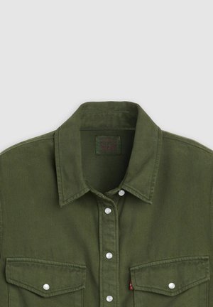 Oliwkowo zielona koszula dżinsowa z ostrym kołnierzem, dwoma kieszeniami na piersiach i srebrnymi zatrzaskami, wykonana z teksturowanego materiału z przeszyciami.