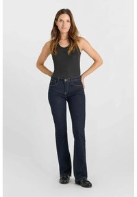Donkerblauwe uitlopende jeans van denim, met een knoopsluiting en zijzakken. Gepaard met een aansluitend zwart tanktop.