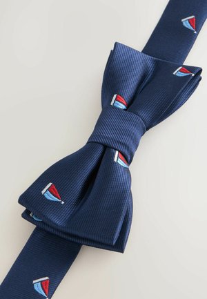 Tummansinen koralli, joka on valmistettu teksturoidusta kankaasta ja jossa on pieniä brodeerattuja purjeveneitä punaisella, valkoisella ja sinisellä.