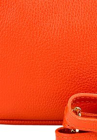 Oranje leren handtas met een bijpassende strap. Beschikt over een gladde afwerking en gestikte accenten die de ronde vorm benadrukken.
