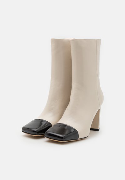 Beige leren enkellaarzen met een vierkante zwarte gepatineerde leren neus. Beschikt over een blokhak en een gladde textuur.