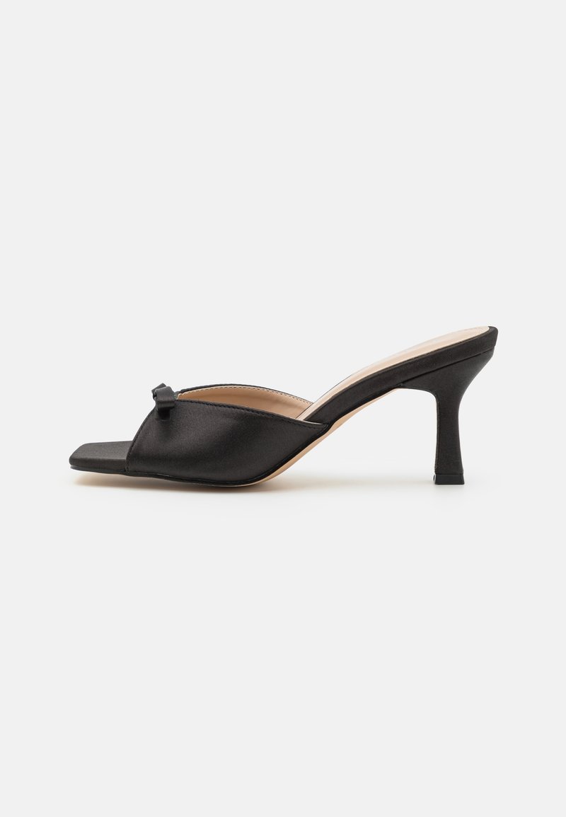 Mules en satin noir avec un bout carré et un petit nœud décoratif. Dotées d'un talon stiletto modéré et d'une texture lisse et brillante.