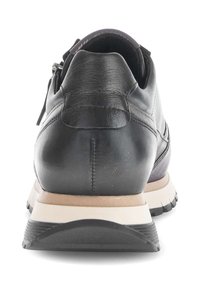 Zwarte leren sneaker met een gladde textuur, gewatteerde kraag, contrasterende zool in beige en zwart, en een ritsdetails aan de zijkant.