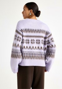 Maglione lavorato a maglia di lillà con una finitura morbida e testurizzata. Presenta motivi geometrici marroni e una vestibilità ampia. Maniche lunghe e spalle scese.