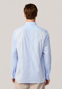 Chemise bleu clair à manches longues avec un col boutonné, présentant un mélange de textures lisses et à rayures sur le dos.