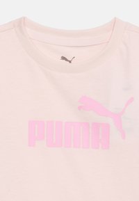Ανοιχτό ροζ μπλουζάκι με στρογγυλή λαιμόκοψη, με έντονο ροζ λογότυπο Puma και γραφικό που απεικονίζει ένα πηδώντας πάνθηρα στο στήθος.