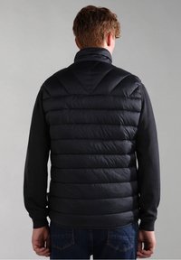 Zwarte puffer gilet met een hoge kraag, voorzien van horizontale gestikte secties en een gladde textuur. Gecombineerd met een zwarte lange mouwen shirt.