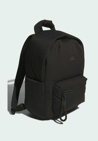 Černý polstrovaný batoh s přední kapsou na zip, textilním poutkem na zip, boční kapsou a horním držadlem na jednobarevném pozadí.