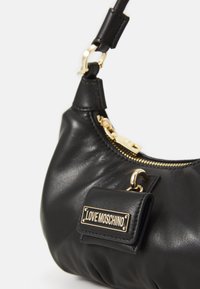 Juodas odinis rankinukas su auksine užtrauktuku ir užsegimu, su mažu pritvirtintu kišeniu, ant kurio yra auksinė "Love Moschino" logotipo plokštelė.
