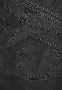 Jeans de mezclilla negra con costuras visibles, cinco bolsillos y una superficie ligeramente texturada. La tela parece suave y duradera.