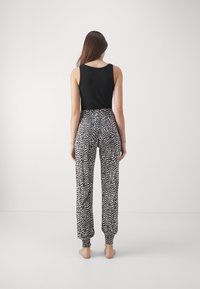 Débardeur noir et pantalon ample noir et blanc à motif avec des poignets élastiques, arborant un design abstrait ondulé.