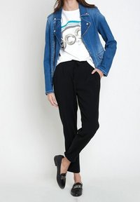 Džínová biker bunda, bílý tričko s metalickým potiskem, černé zúžené kalhoty a černé polobotky se zdobením.