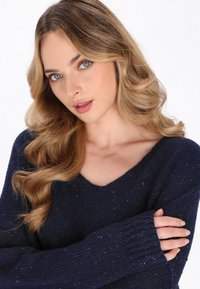 Marineblauer gestrickter Pullover mit V-Ausschnitt, gerippten Ärmelbündchen und strukturierter Oberfläche, ausgestattet mit langen Ärmeln und einem lässigen Schnitt.