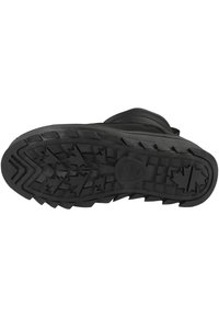 Suela de bota de goma negra con un patrón de banda de rodadura profundo y agresivo. Presenta una forma redondeada y un detalle del logo en el centro. Superficie duradera y texturizada.